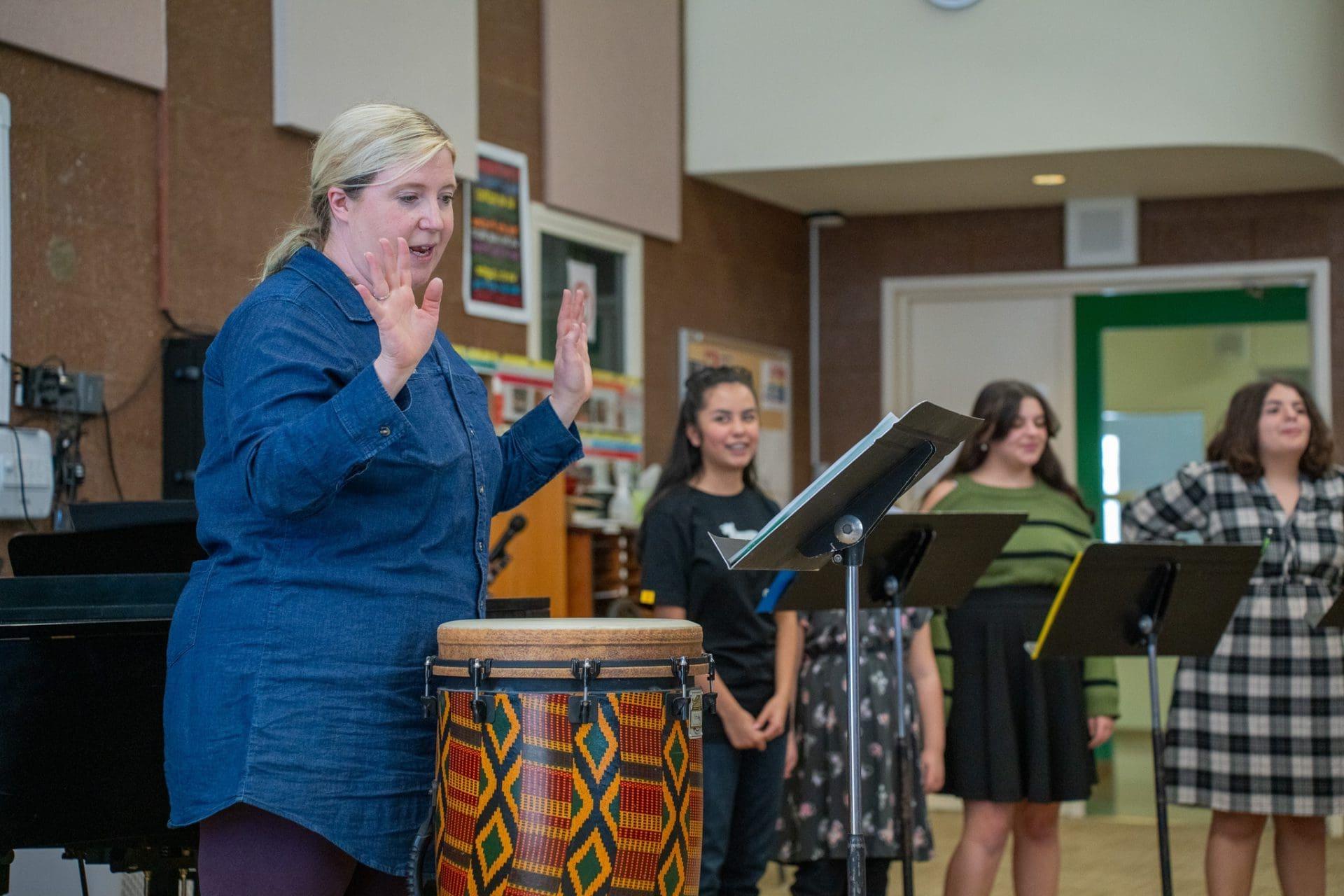 亩ic teacher conducting choir rehearsal with students.